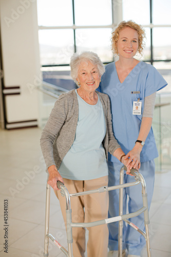 Nurse helping senior patient with walker in hospital corridor