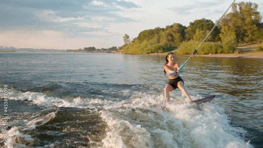A female surfer jumping on a wakeboard. An experienced wakeboarder splashes water drops into the camera. A female surfer jumping on a wakeboard. An experienced wakeboarder splashes water drops into the camera.