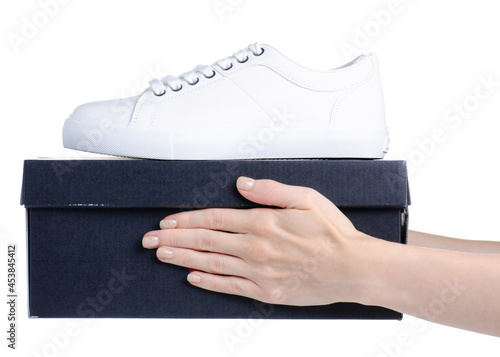 White leather keds sneakers with black box in hand on white background isolation