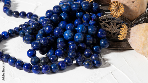 Beautiful bright  round blue lapis lazuli beads close up on a white background. Vintage composition. photo
