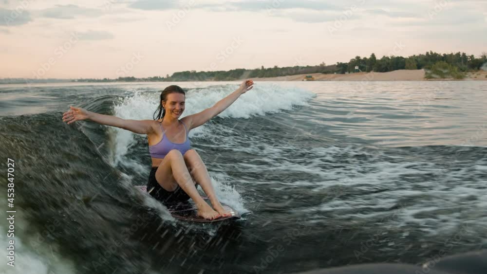 A female surfer jumping on a wakeboard. An experienced wakeboarder splashes water drops into the camera. A female surfer jumping on a wakeboard. An experienced wakeboarder splashes water drops into the camera.