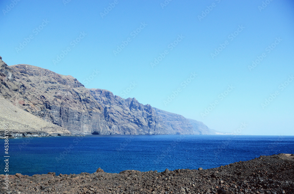 Fototapeta premium TENERIFE, SPAIN: Scenic seashore view of Los Gigantes ancient rocks with blue sea waters