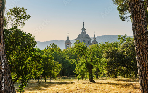 Sunset view of the dome and towers of the San Lorenzo de el Escorial monastery from a forest in early autumn and the mountains in the background. photo