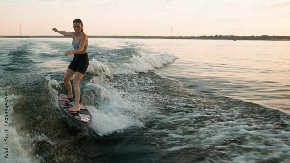 A female surfer jumping on a wakeboard. An experienced wakeboarder splashes water drops into the camera. A female surfer jumping on a wakeboard. An experienced wakeboarder splashes water drops into the camera.