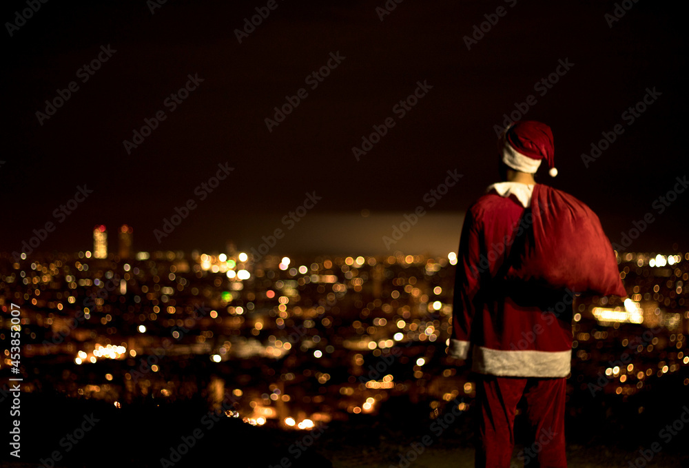 Papa Noel de espaldas mirando la ciudad de noche