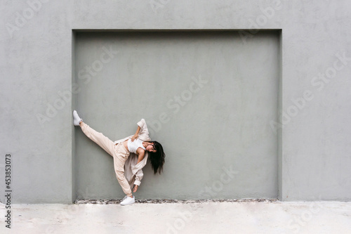 Graceful dancer performing near wall in city street photo