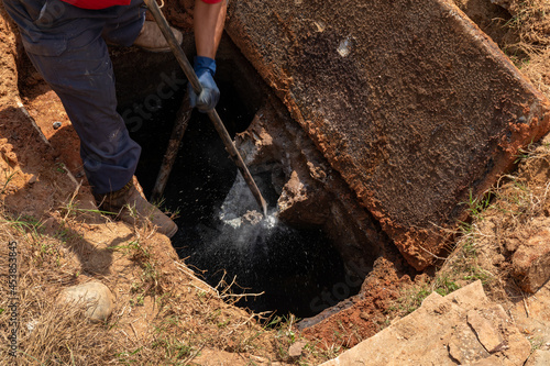Man breaking apart a wastewater outlet in an old septic tank to bring it up to code, horizontal aspect photo