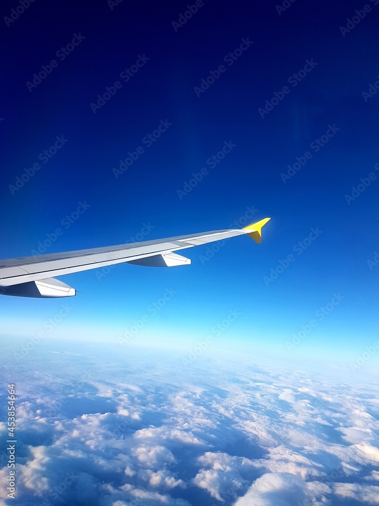 Alas de un avión en pleno vuelo. Vistas desde la ventana del avión. Dia nublando, cielo azul Alas de un avión en pleno vuelo. Vistas desde la ventana del avión. Dia nublando, cielo azul