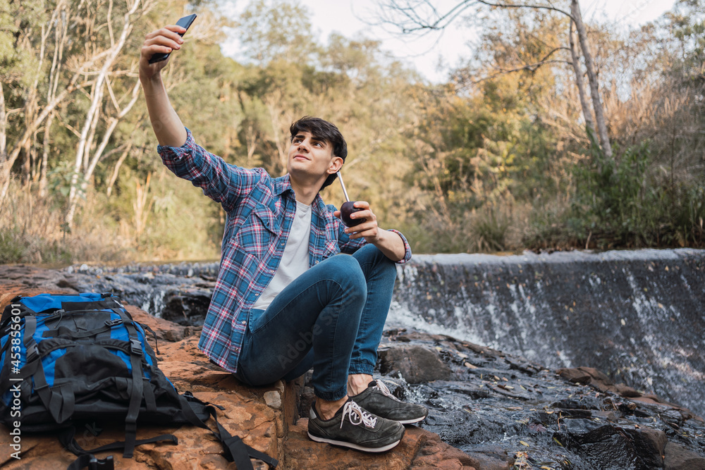 Smiling traveling man taking selfie with smartphone during hike Smiling traveling man taking selfie with smartphone during hike