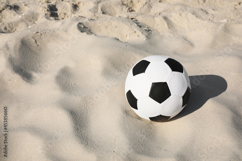 Soccer ball on sand, space for text. Football equipment © New Africa