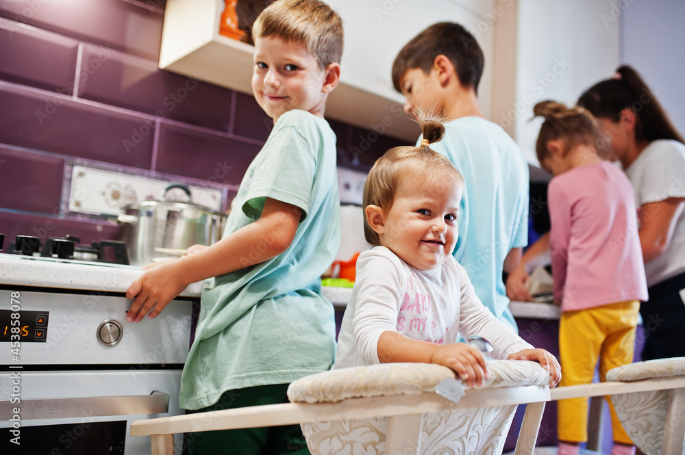 Mother with kids cooking at kitchen, happy children's moments.