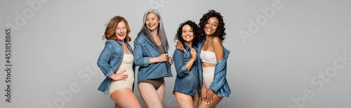 Positive multiethnic women in lingerie and denim shirts isolated on grey, banner