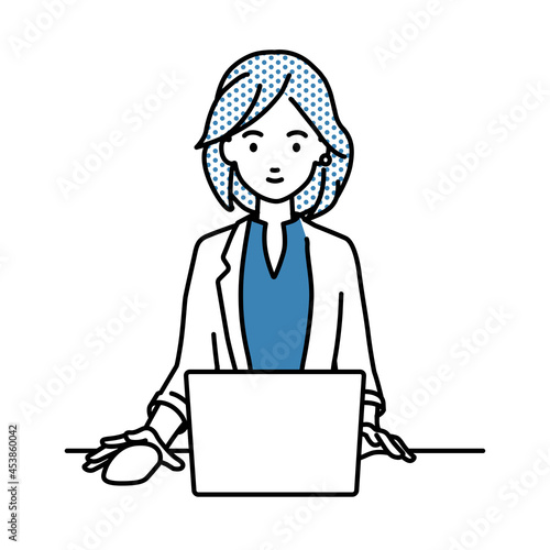 デスクで座ってPCを使っているジャケットの女性