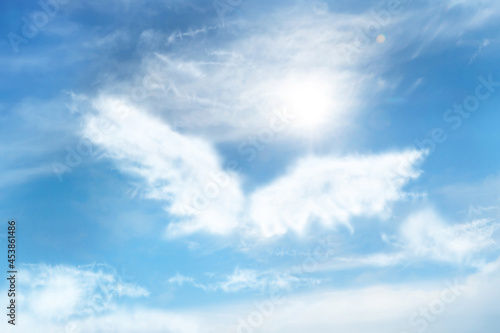 Silhouette of angel's wings made of clouds in blue sky