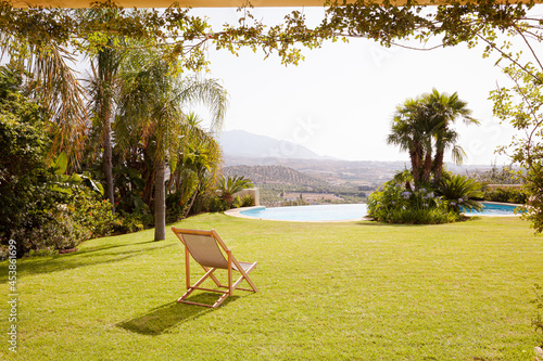 Lawn chair in grass overlooking swimming pool