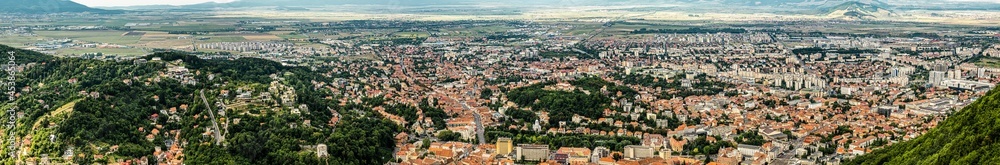 Aerial panoramic view of Brasov surrounded by the Carpathian mountains dotted with ski resorts including the ever popular Boiana Brasov. Romania, the Balkans, Eastern Europe