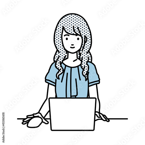 デスクで座ってPCを使っているオフィスカジュアルの女性