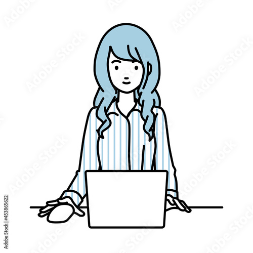 デスクで座ってPCを使っているブラウスの女性