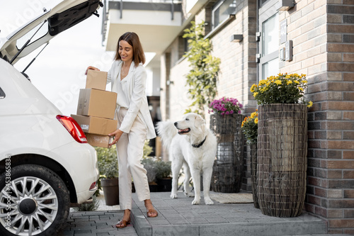 Woman with a parcels near her car and home photo