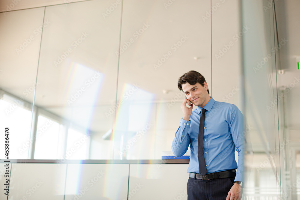 Businessman talking on cell phone in office Businessman talking on cell phone in office