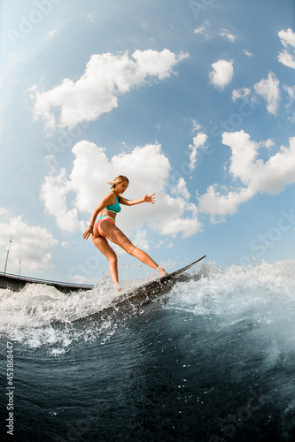 attractive young woman wakesurfer skilfully balancing on surfboard along the river wave © fesenko