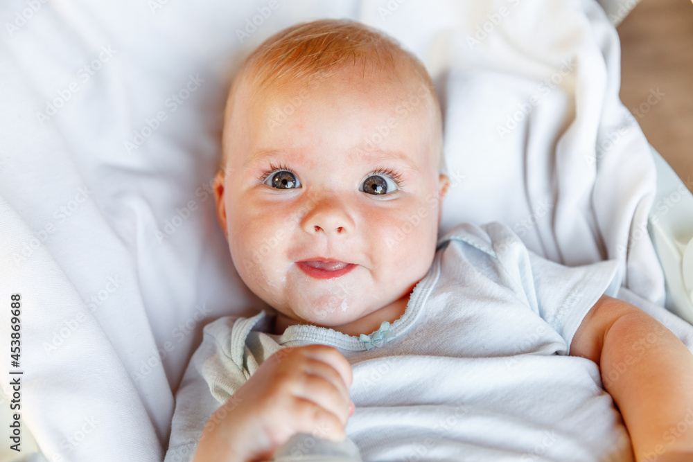 Cute little newborn girl with smiling face looking at camera on white background. Infant baby resting playing lying down on crib bed at home. Motherhood happy child concept Cute little newborn girl with smiling face looking at camera on white background. Infant baby resting playing lying down on crib bed at home. Motherhood happy child concept