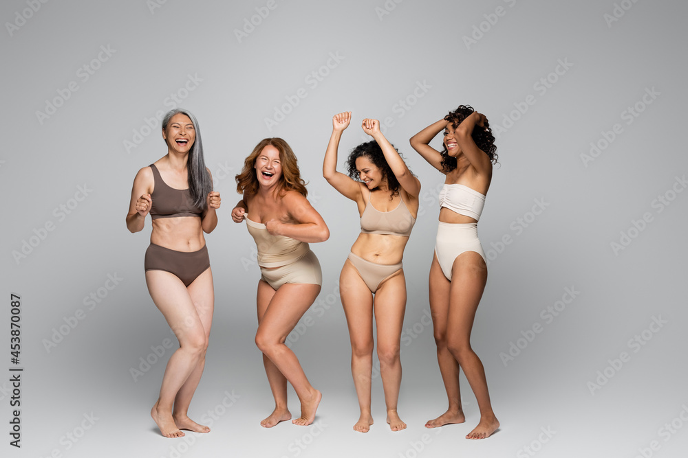 Positive interracial women in underwear on grey background - obrazy, fototapety, plakaty 