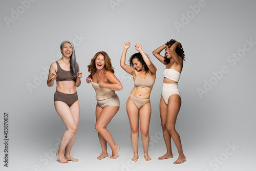 Positive interracial women in underwear on grey background photo