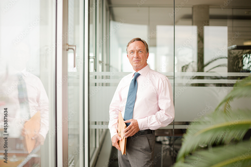 Businessman standing at office window Businessman standing at office window