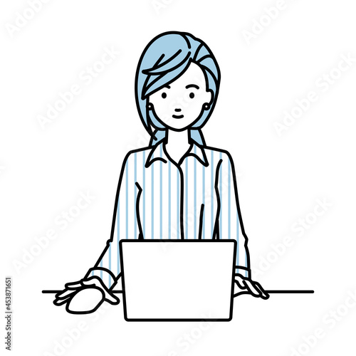 デスクで座ってPCを使っているブラウスの女性