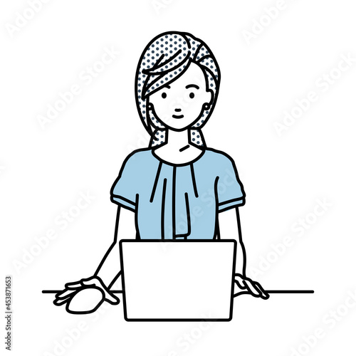 デスクで座ってPCを使っているオフィスカジュアルの女性