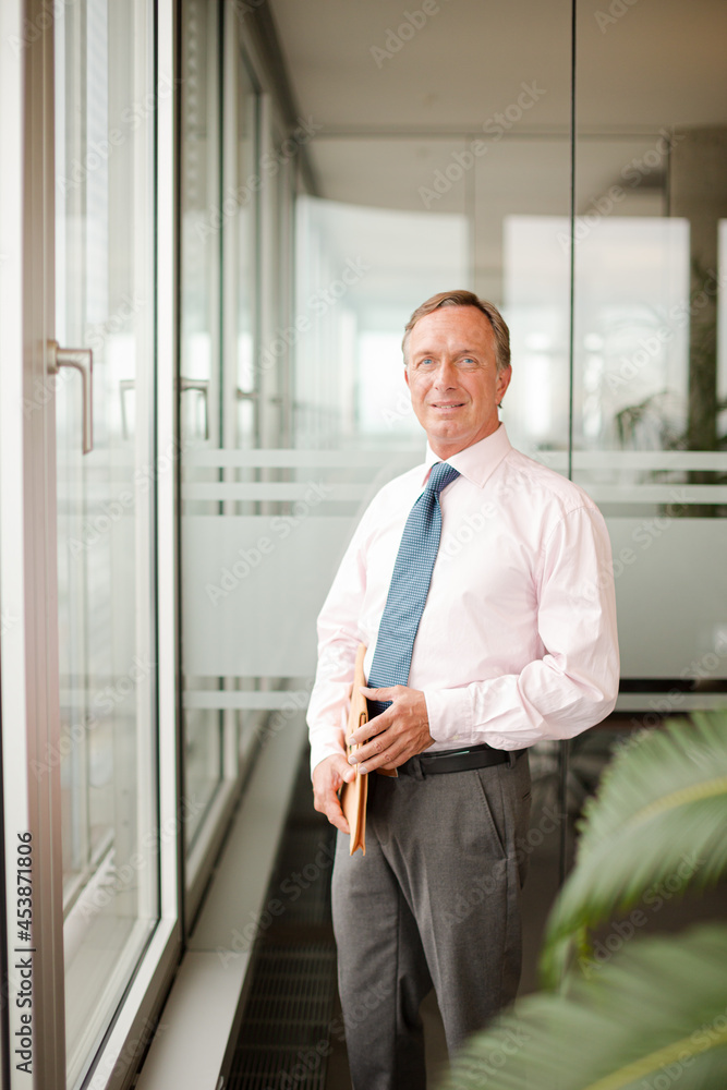 Businessman standing at office window Businessman standing at office window