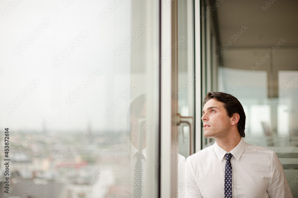 Businessman standing at office window Businessman standing at office window