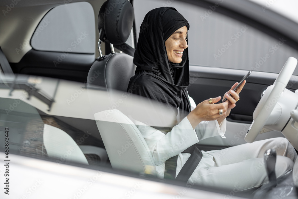 Muslim woman talks on phone while driving a car