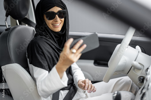 Muslim woman talks on phone while driving a car © rh2010