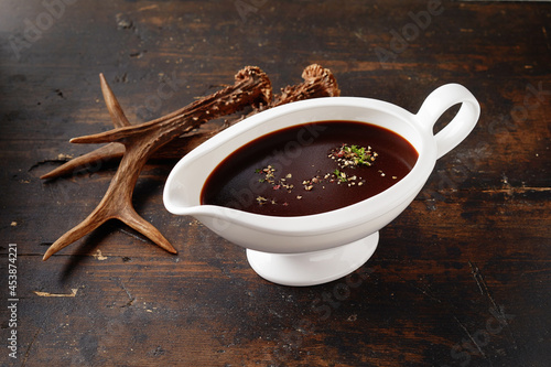 Gravy boat with brown sauce near deer horn photo