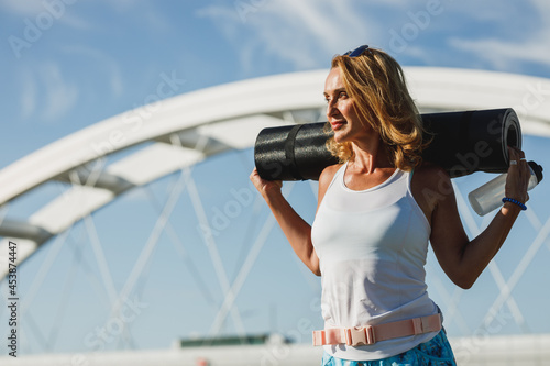 Woman Holding Rolled Up Exercise Mat © milanmarkovic78