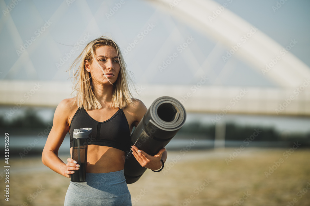 Woman Holding Rolled Up Exercise Mat And Water Bottle And Preparing For Outdoor Working Out