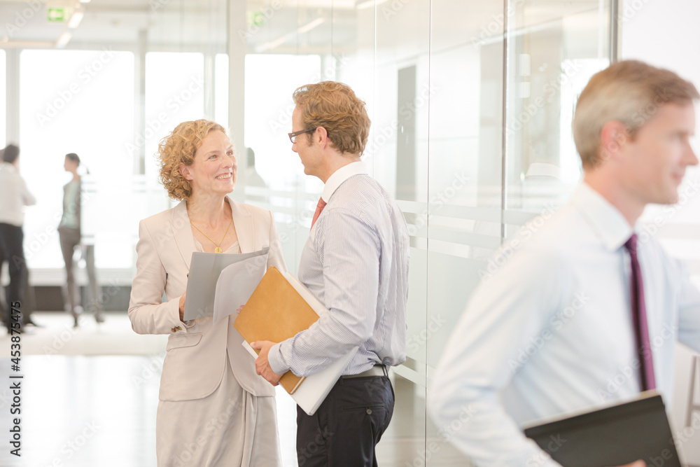Business people smiling in office lobby Business people smiling in office lobby