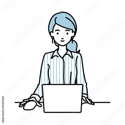 デスクで座ってPCを使っているブラウスの女性