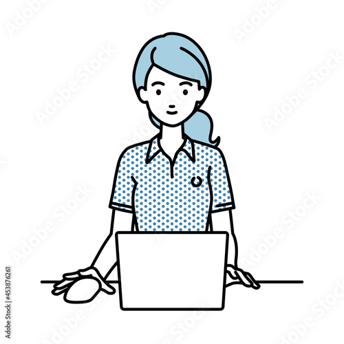 デスクで座ってPCを使っているポロシャツの女性