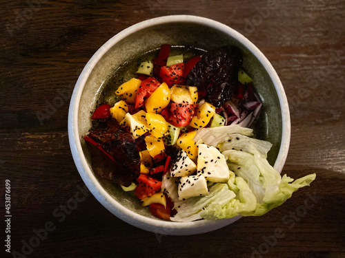 Choban salad of cucumbers, tomatoes, bell peppers and cheese in a white plate on an isolated wooden background photo