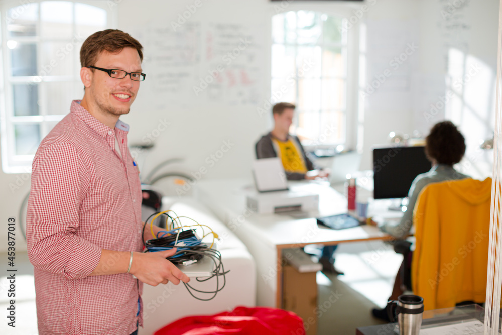 Fototapeta premium Businessman carrying cords and laptop in office
