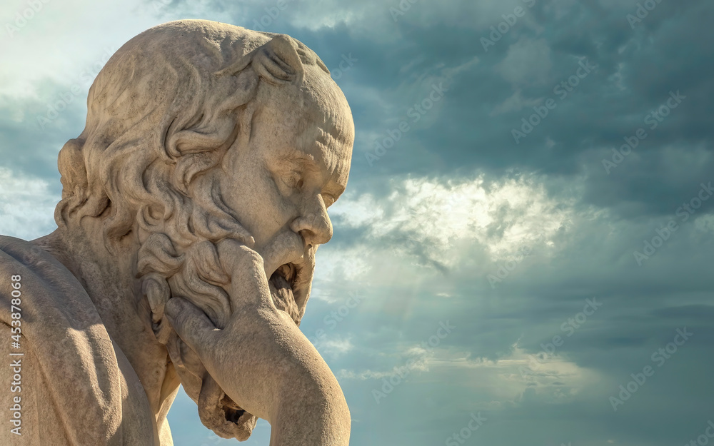 Socrates in deep thoughts, the ancient Greek philosopher marble statue under dramatic cloudy sky