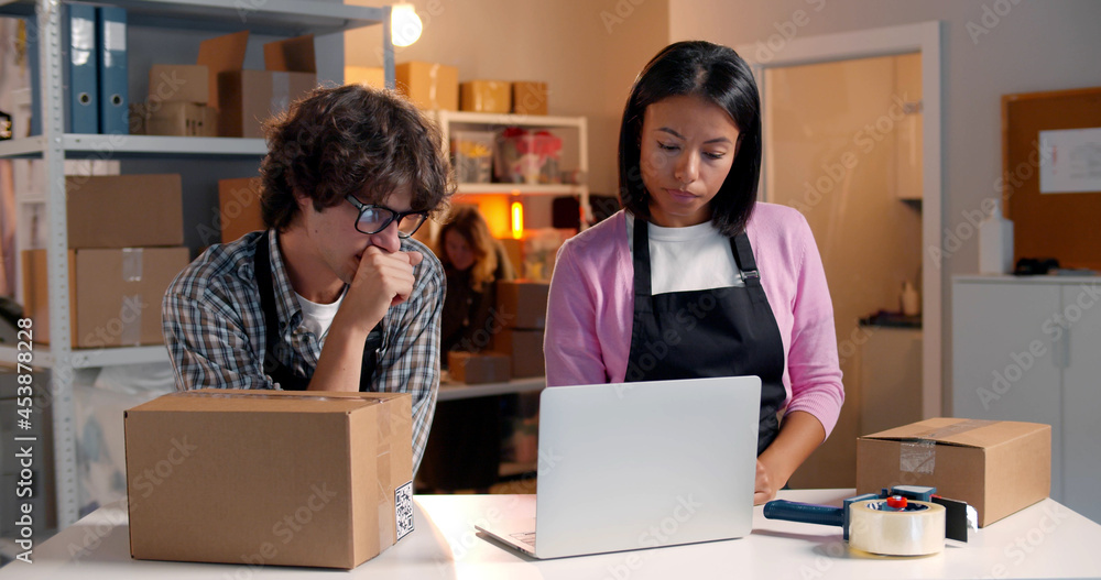 Small business owners checking order to confirm before sending customer in post office Small business owners checking order to confirm before sending customer in post office
