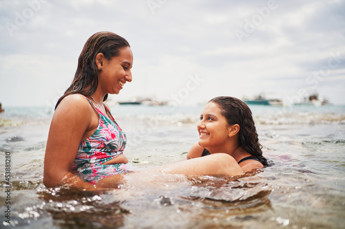 Two cheerful young women smiling in a natural pool in beach