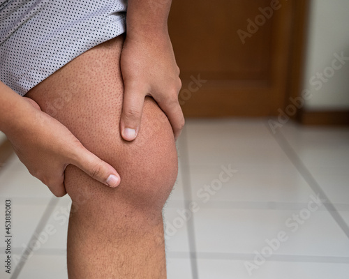 Man massages swollen knee caused by gout attack