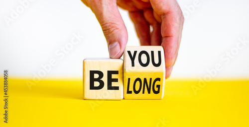 Be you, belong symbol. Businessman hand turns a cube and changes words 'be you' to 'belong'. Beautiful white and yellow background. Business, belonging and be you, belong concept. Copy space.