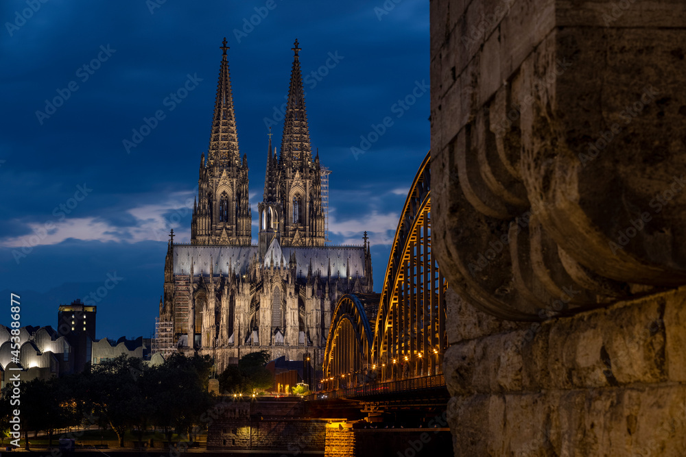 Historical buildings illuminated against blue hour sky late in summer in Cologne