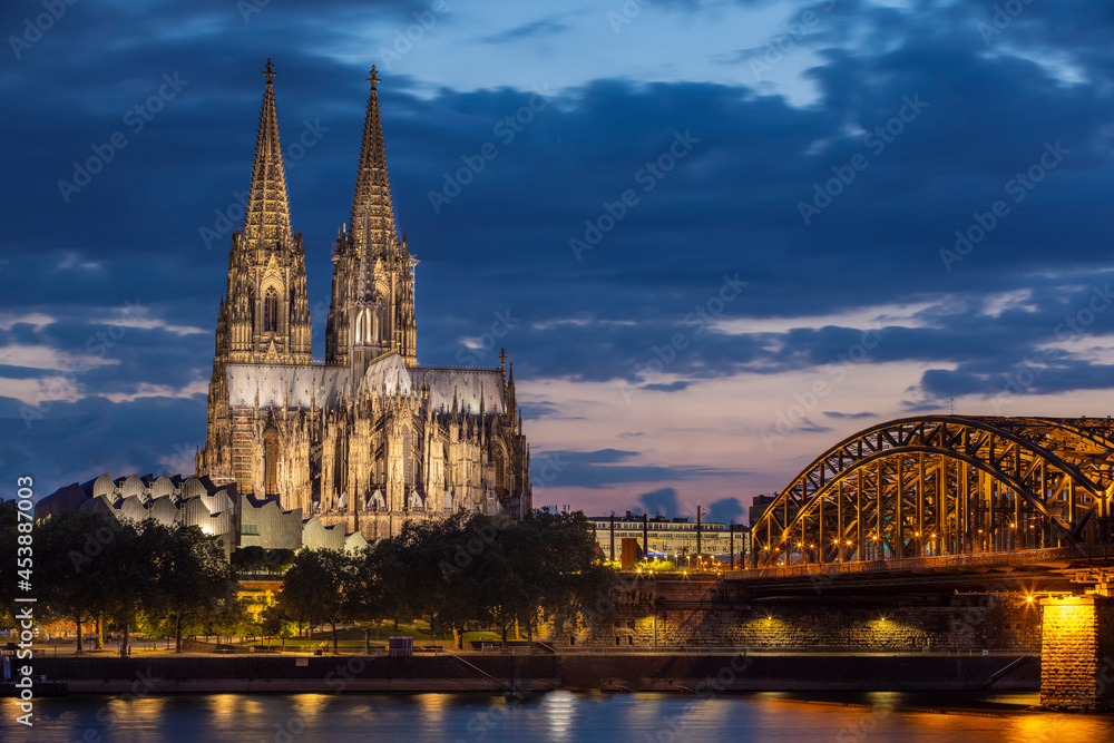 Naklejka premium Historical buildings illuminated against blue hour sky late in summer in Cologne
